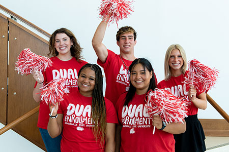 Dual Enrollment students, in matching t-shirts, shake red and white pompoms in a group photo