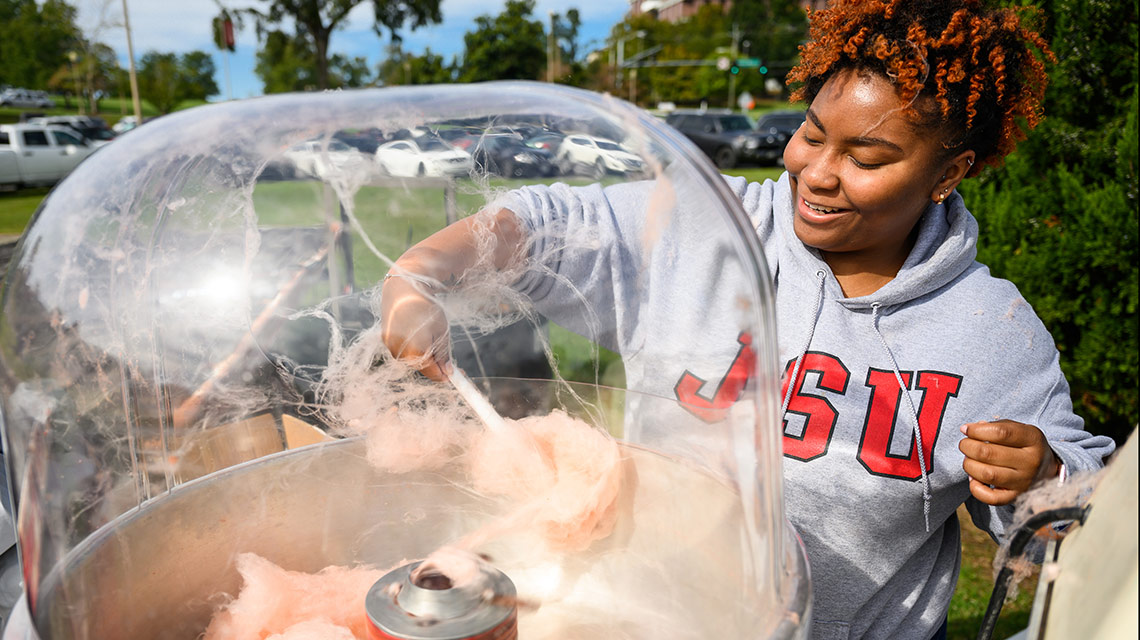 A volunteer works the cotton candy machine at the Homecoming Carnival