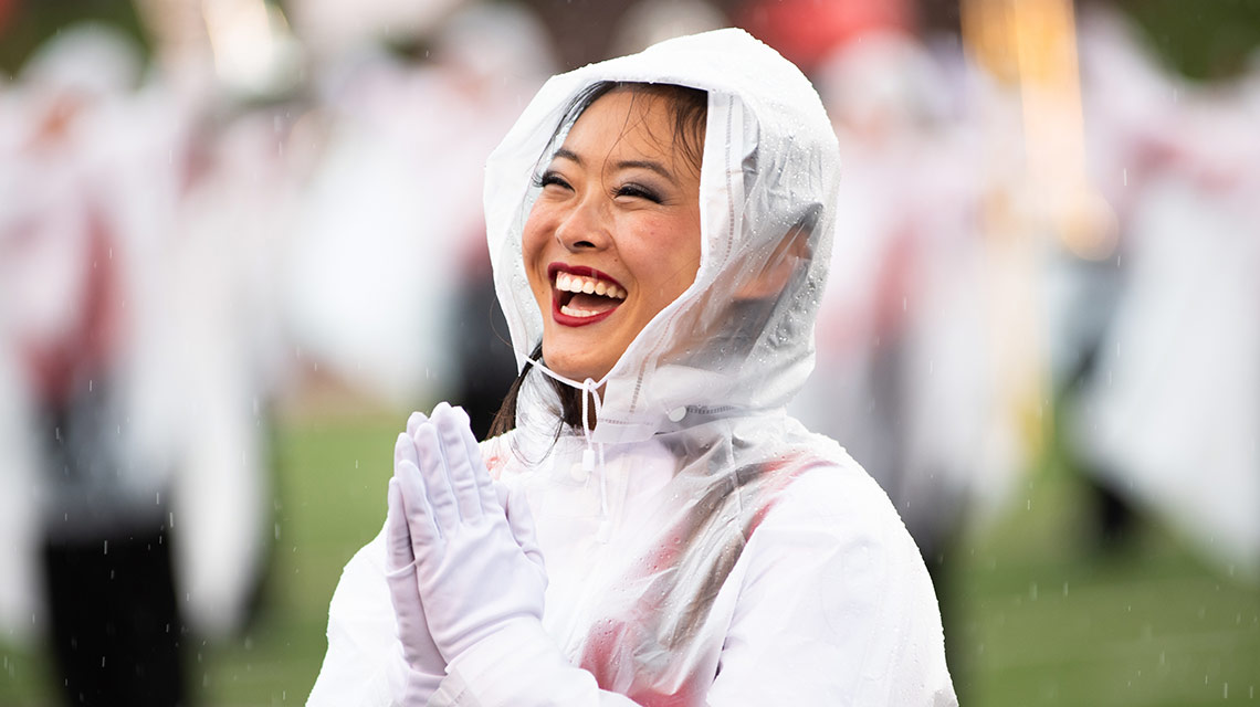 A smiling ballerina in a poncho during pre-game festivities