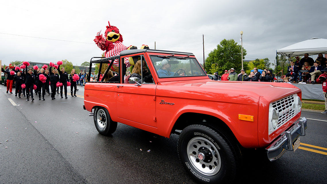 Cocky riding on a vintage red Ford Bronco in the Homecoming Parade