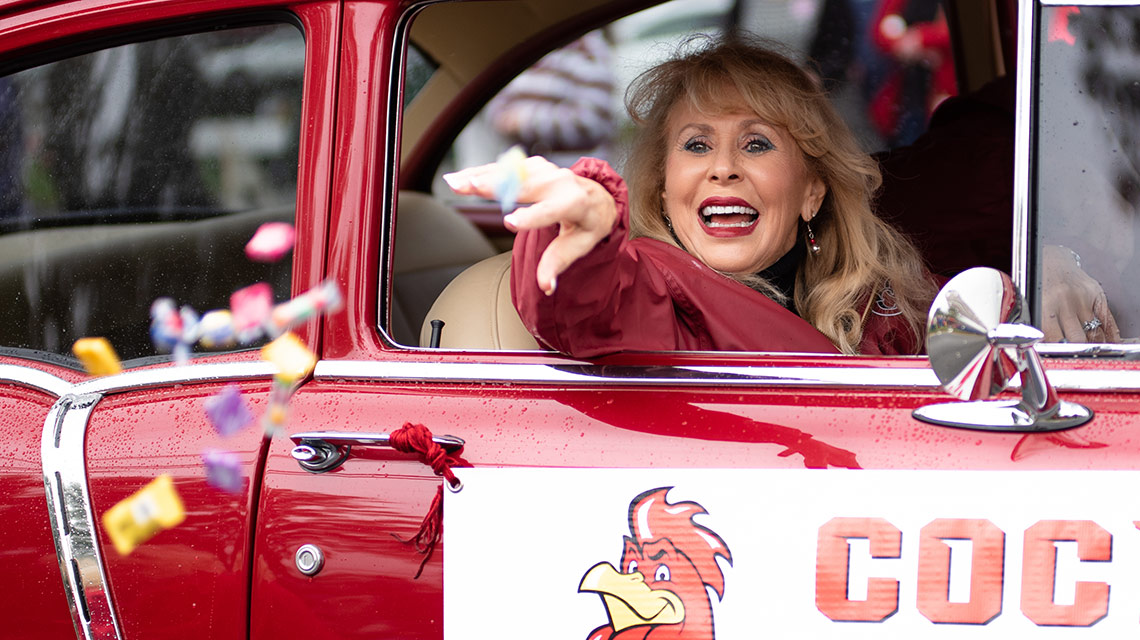 Jenny Howell, riding in a red car, tosses candy at the crowd