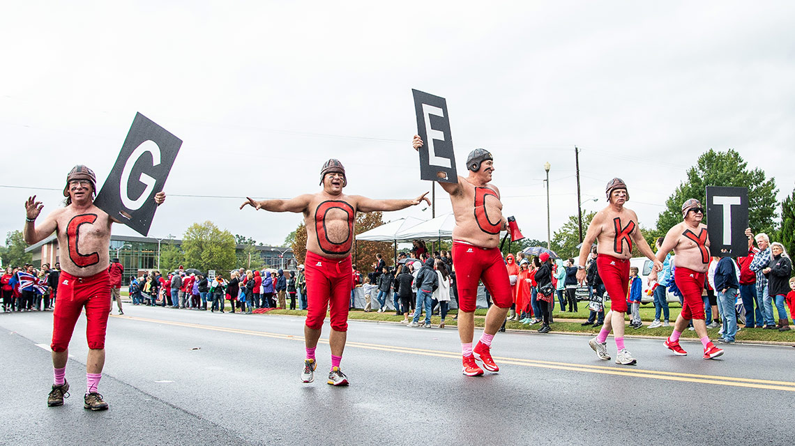 The Elite Lettermen spell out the phrase Get Cocky in signs and body paint during the homecoming parade