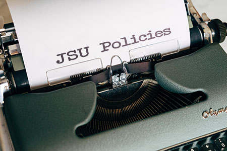 Typewriter typing paper with text JSU Policies
