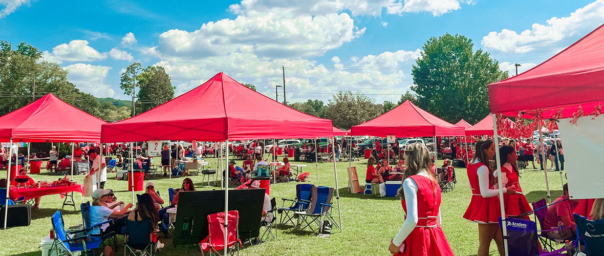 A sea of crowded red Roost tailgate tents stand out under a blue game day sky in autumn.