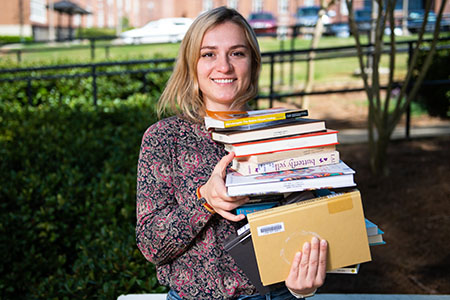 A student holding a stack of textbooks ready for her classes at JSU