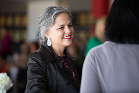 An adult learner speaking with her professor on campus