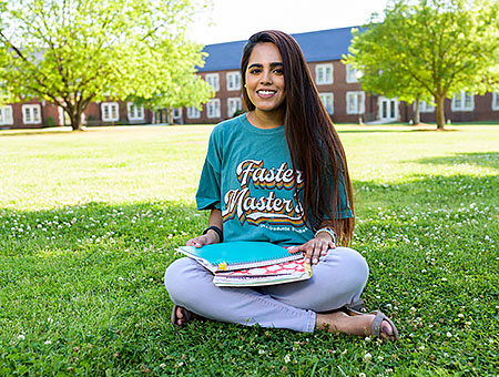 Graduate Student sitting on grass of JSU Quad