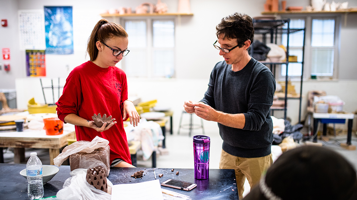 Professor and Student reviewing a ceramics piece. 