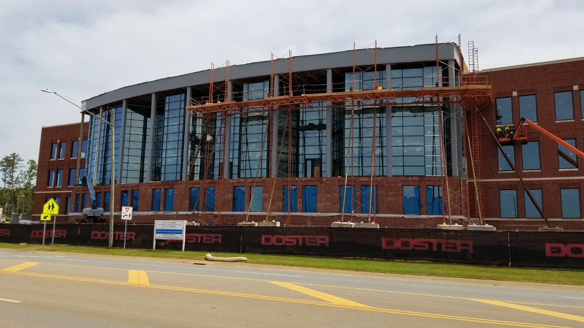 The sky is reflected as workers continue to install the wall of glass on the front of the new Merrill Hall