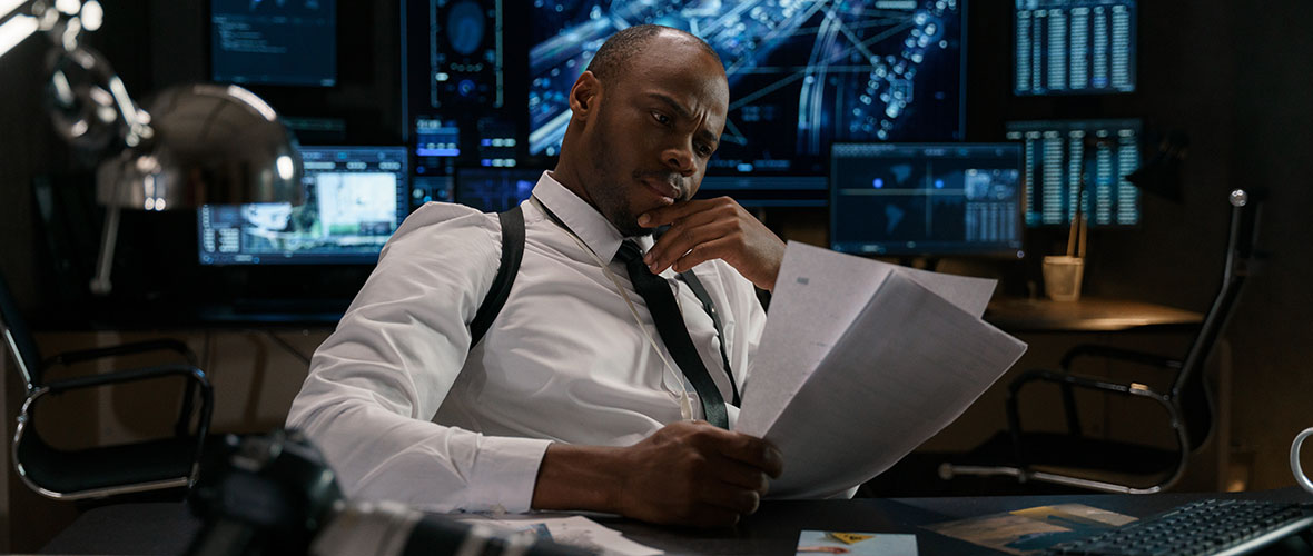 Detective sitting behind desk studying papers