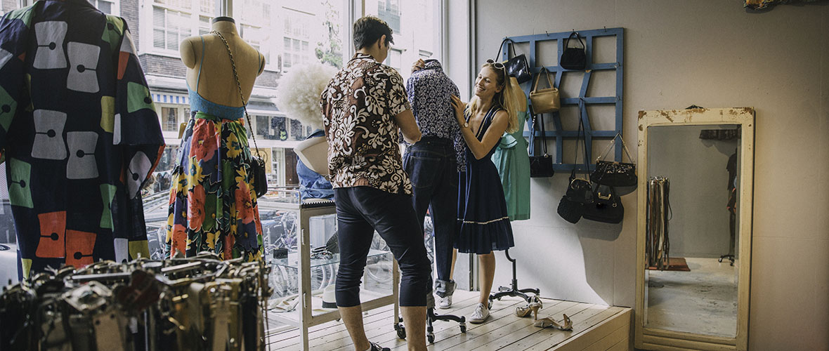 Two store merchandisers decorate the window with the latest fashion