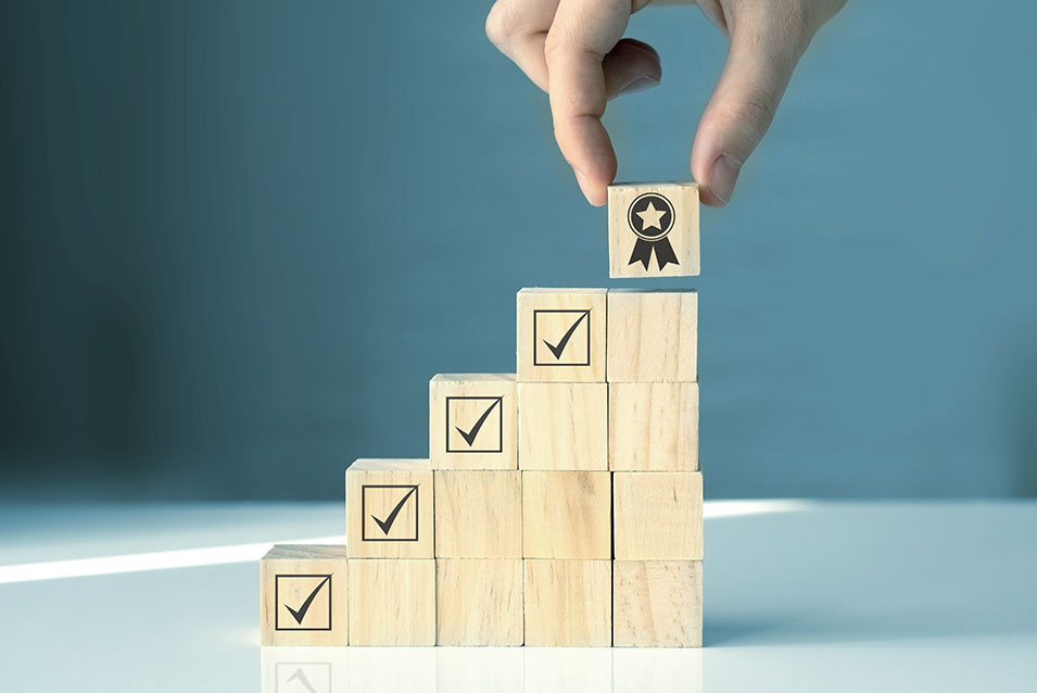 stacks of blocks with checkmarks, with the top block being marked with a ribbon