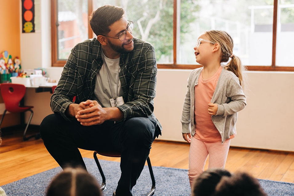 A male teacher laughs with one of his students