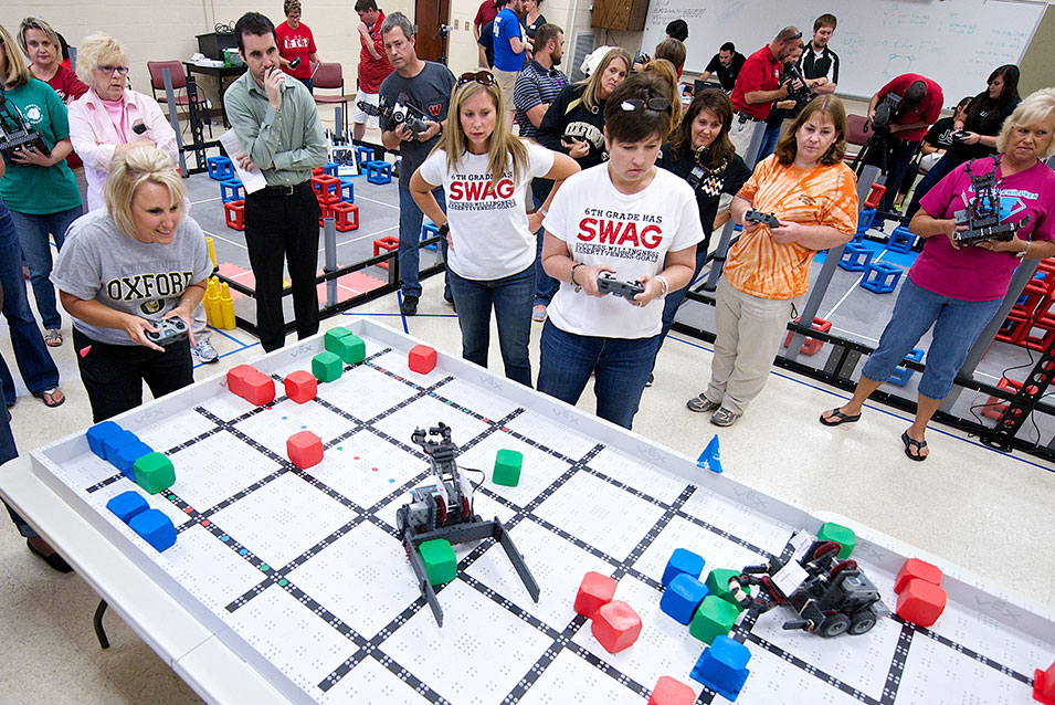 Teachers control robots with game controllers during an Inservice training.