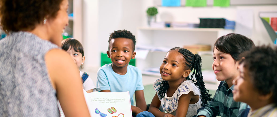 An African American teacher reads to her young students