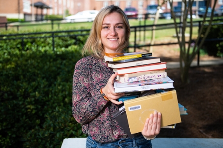 A student holding stacked books.