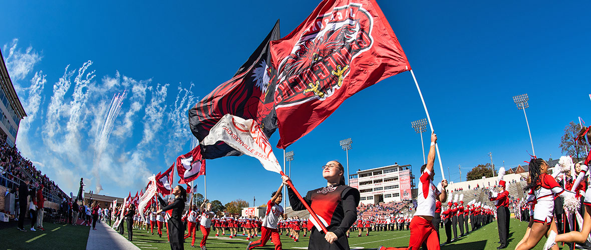 The spirit of Homecoming 2021- Fireworks explode in a beautiful blue afternoon sky over JSU Stadium while Southerners perform on the field with JSU flags flying and the cheerleaders lead the team in above the roar of the crowd.