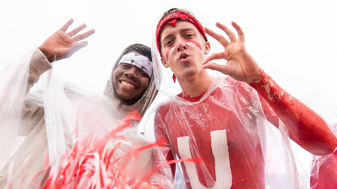 Male students wearing body paint and rain ponchos "fear the beak" at the homecoming game in the rain