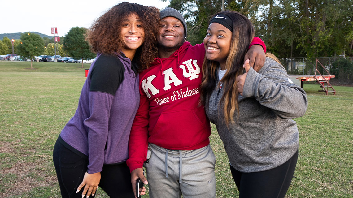 Three female students embrace at the shrimp boil