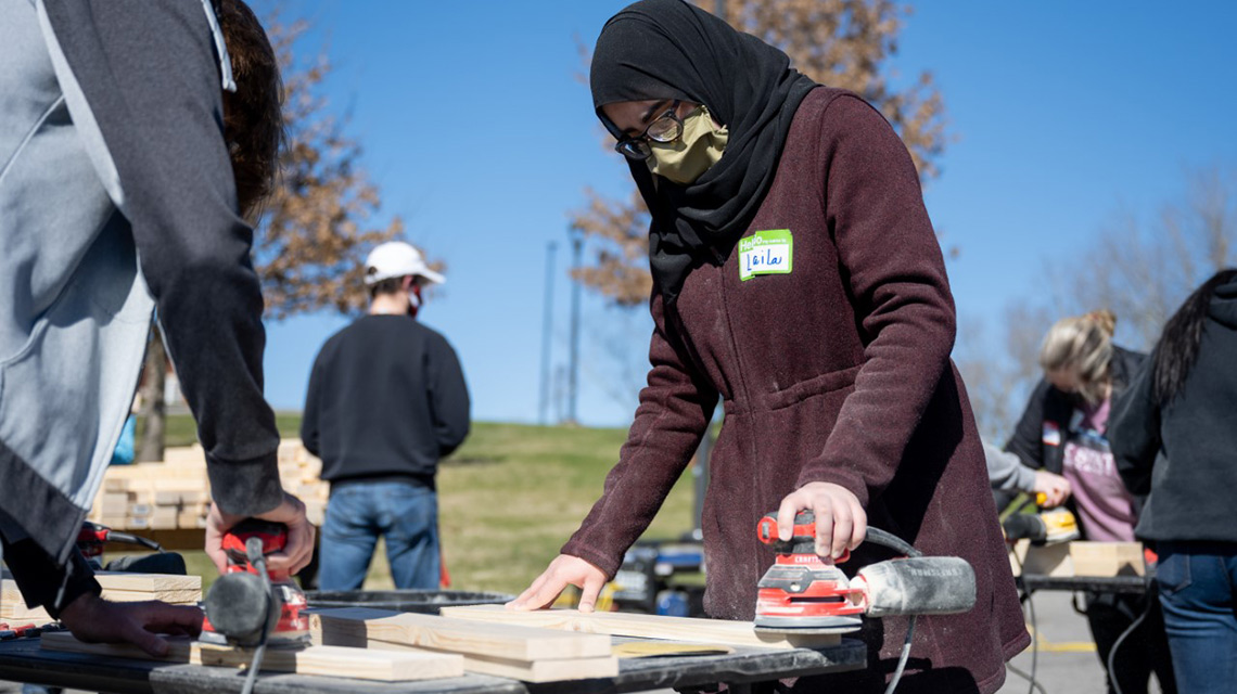 Students use power tools to build beds during the bed building drive