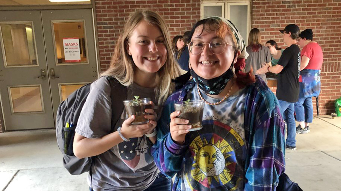 Students hold their terrariums made at the Terrarium party