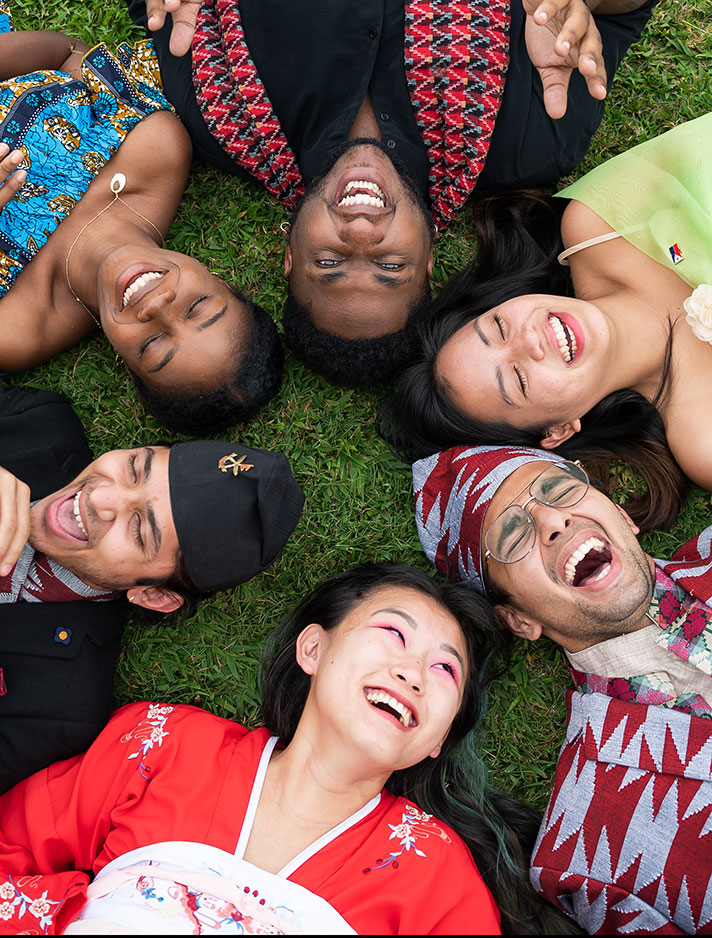 International students in their native dress lie head to head in a circle of friendship