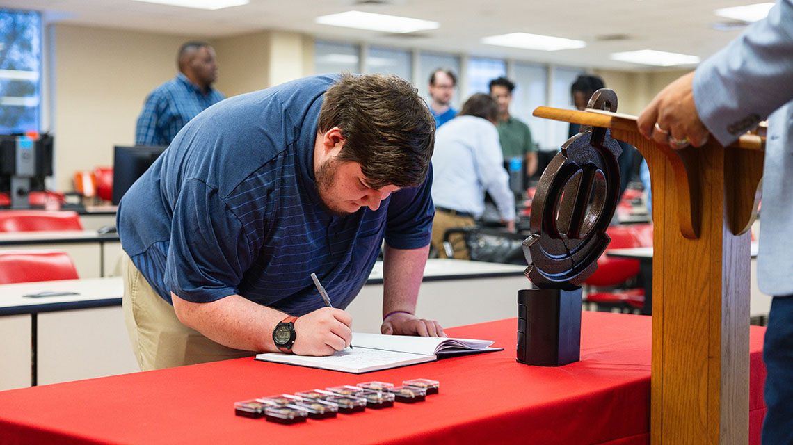 A student signs the roll