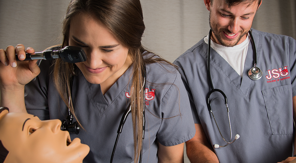 nursing students examining 'patient' in lab