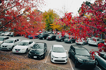 A full JSU parking lot, framed by trees displaying bright fall colors
