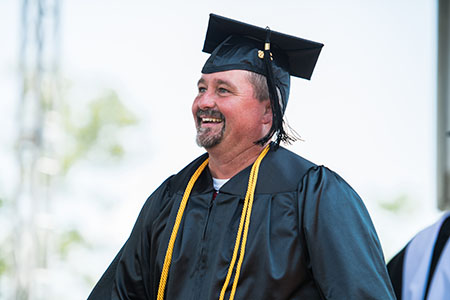 A student proudly walking on stage to graduate