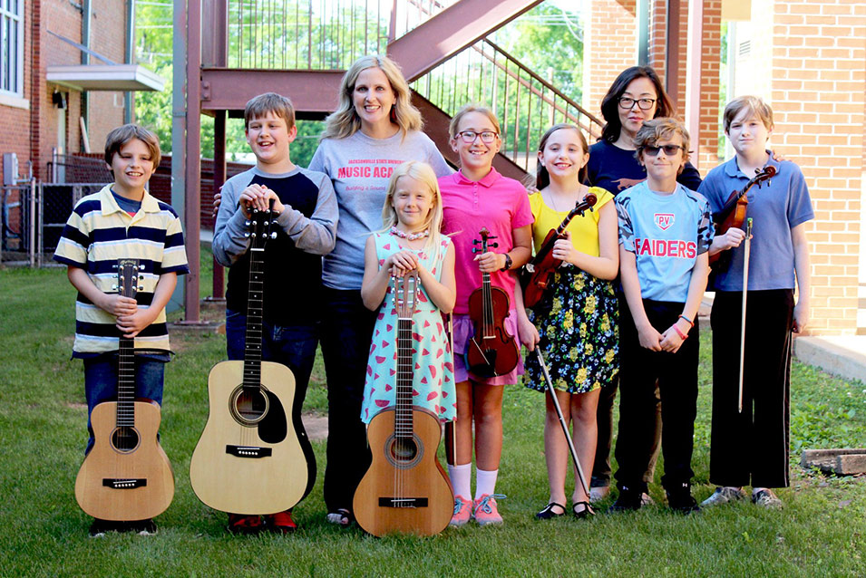 Children who were participants in the JSU Summer Music Academy stand with their guitars and their teachers