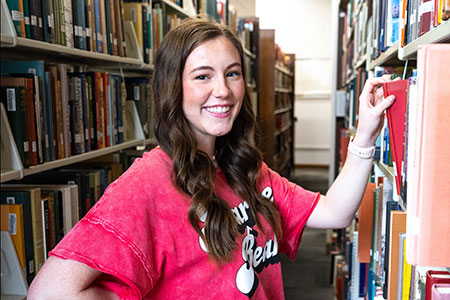 A female student selects a book from the stacks at the Houston Cole Library.