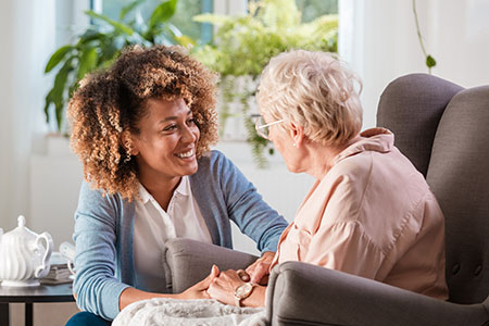 A social work student visits with an elderly patient during a home visit