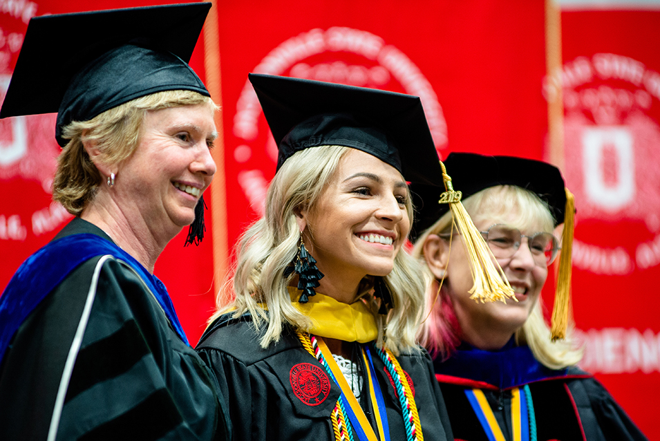 Social work master's degree recipient with faculty at hooding ceremony