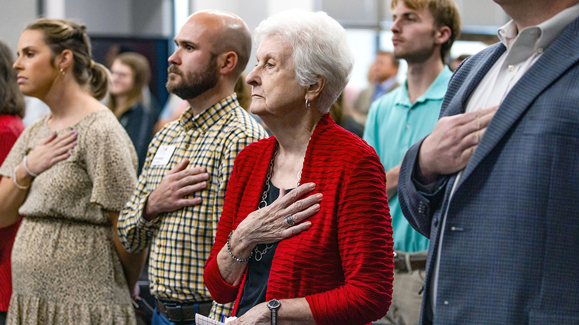 The audience stands with hands over heart as the Jacksonville State University Army ROTC Color Guard presented the National Colors of The United States of America while Mr. Brady Drake sang the National Anthem.