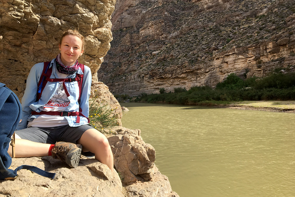 Madeline Miles on the river with rock formations on canyon walls