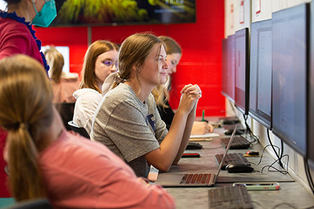 A girl sitting at a computer looking at the screen