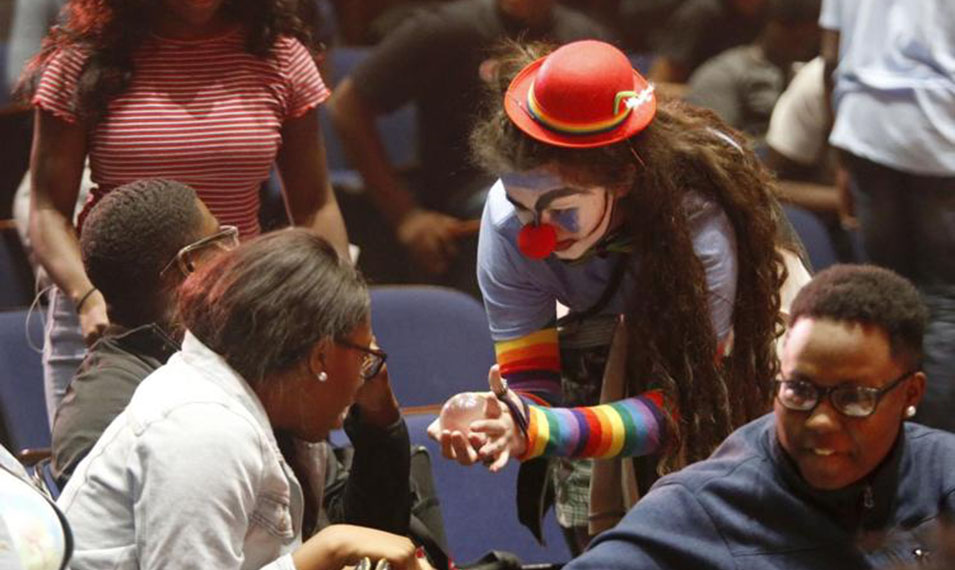 A clown entertains  audience members