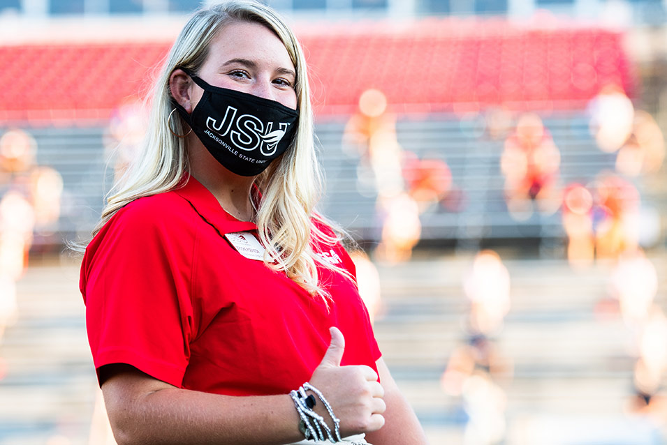 female student in mask giving a thumbs up sign