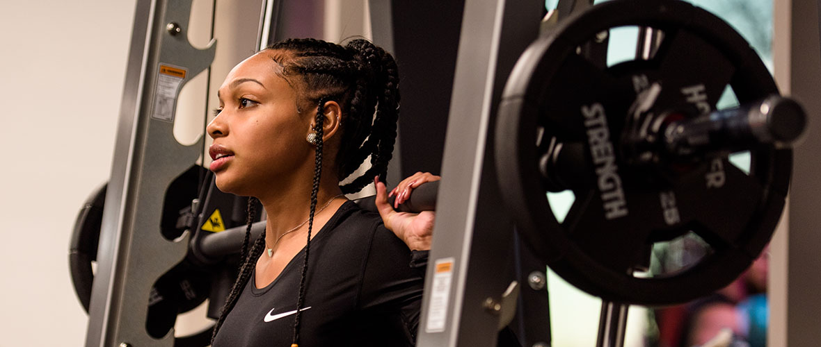 Female student gets ready to do a weighted squat.