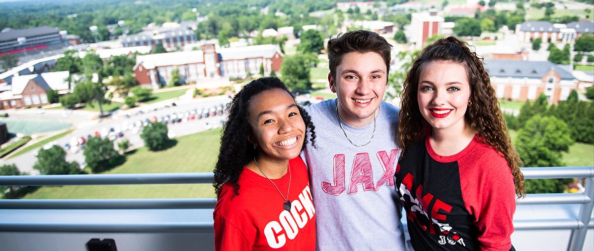 Three JSU Ambassadors on Houston Cole Library observation deck, with a view of the west side of campus behind them.