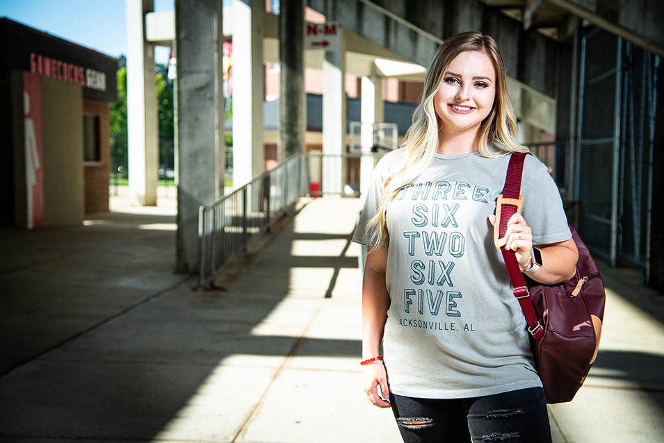 student with backpack at stadium